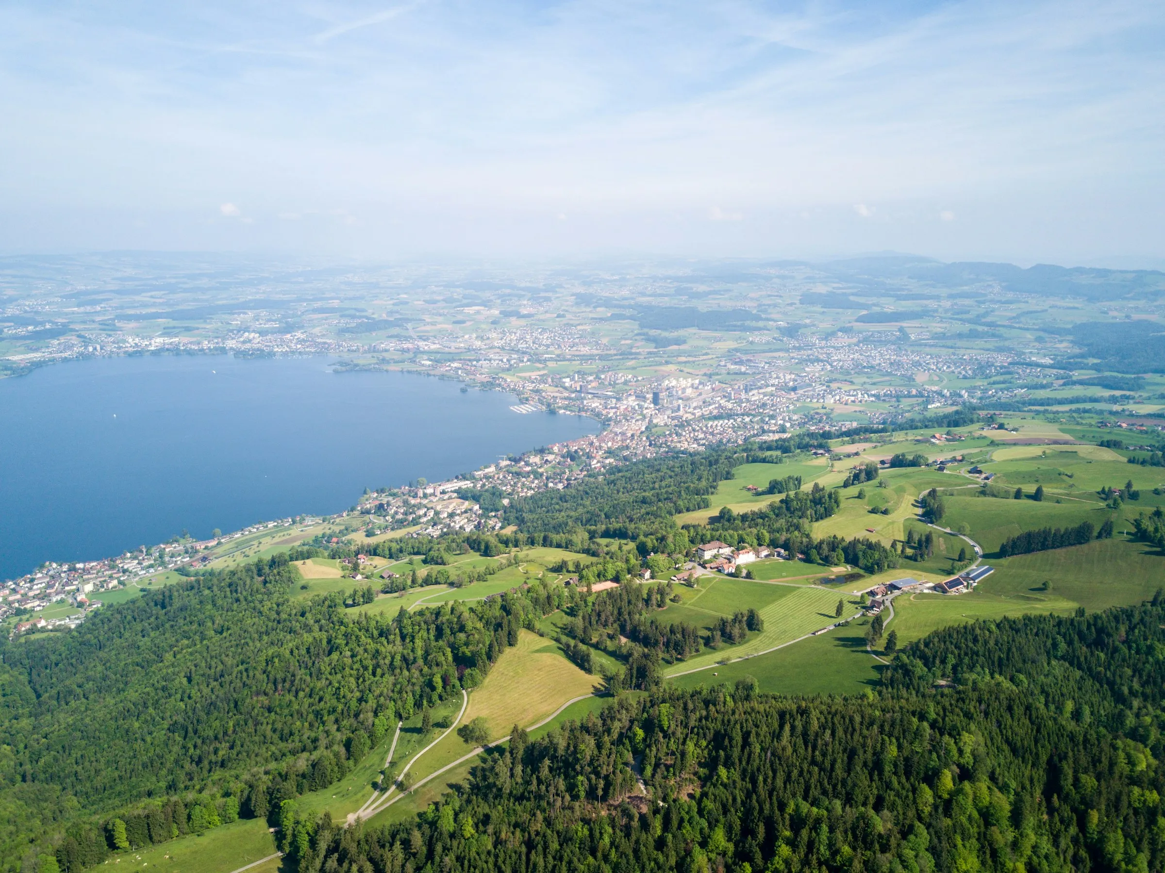 Luftbild bei Zug mit Wiesen, Waldrändern, Siedlung und Zugersee